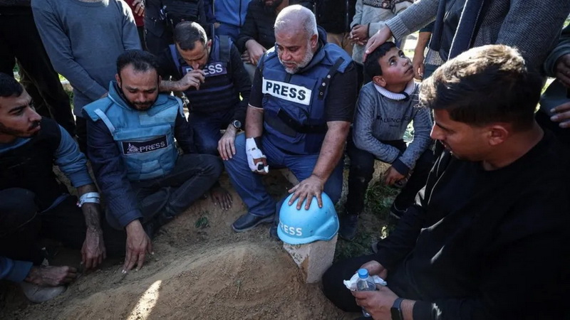 Wael al-Dahdouh accarezza un casco “stampa” posto sulla tomba del figlio, il giornalista Hamza al-Dahdouh. © Loay Ayyoub