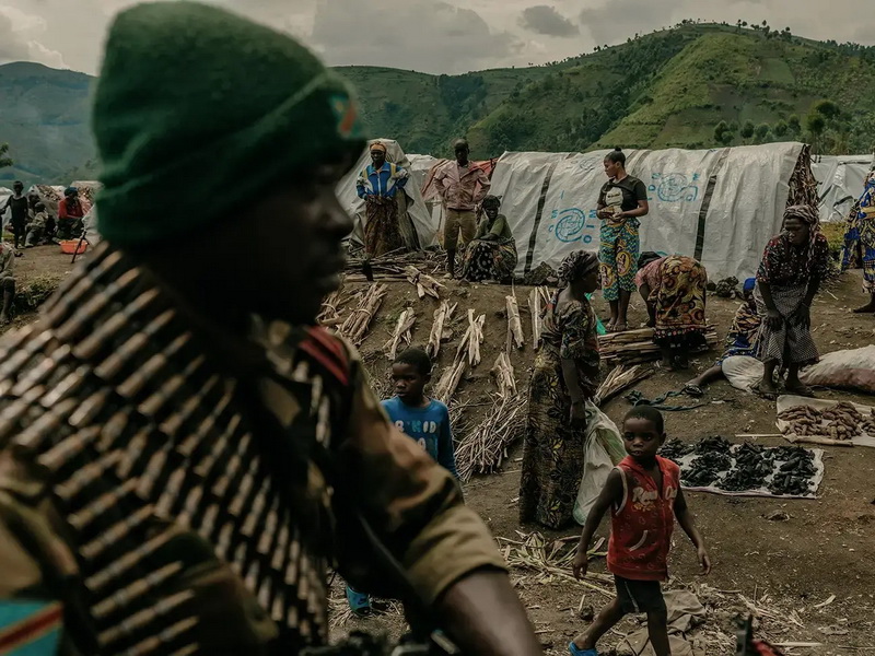 8 aprile 2023, Sake, provincia del Nord Kivu, Repubblica Democratica del Congo. Soldati delle Forze Armate della RDC passano davanti al campo profughi di Zaina che si sta svuotando con l'avvicinarsi della linea del fronte. © Hugh Kinsella